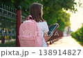 Teenage girl walks down street with tablet in hand. Student hurries to school lesson city street carrying digital tablet. Child with backpack on back hurries to school. Children education concept 138914827