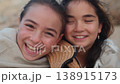 Cheerful young sisters wrapped in blanket laughing 138915173