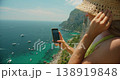 Young woman recording phone video of boats on the blue sea from a sunny viewpoint in Capri 138919848