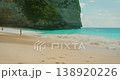 Distant woman enjoying vacations on sandy shore with white foam ocean waves 138920226