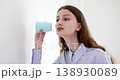 Concentrated woman listens in glass to discussion of friends in office behind wall 138930089