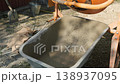 Working process of mixing concrete for the foundation of a private house, cement mortar is poured from a concrete mixer into a wheelbarrow. 138937095