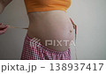 Expectant mother carefully wrapping a measuring tape around her pregnant belly, meticulously checking the size and progress of her baby's growth during a happy and healthy pregnancy 138937417
