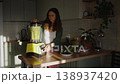 Pregnant woman preparing a healthy green smoothie with a blender in her cozy, sunlit kitchen. Expectant mother focusing on a nutritious diet, blending vegetables for a vitamin-rich drink 138937420