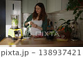 Expectant mother carefully preparing a nutritious green detox smoothie in her sunlit kitchen, adding fresh vegetables and herbs to a blender for a healthy diet during her pregnancy 138937421