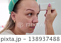 Woman applying a skincare device at home during morning routine to enhance beauty and wellness 138937488