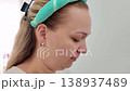 Woman with a hairband focusing on a task in a bright and cozy indoor setting 138937489