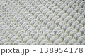 An industrial conveyor is in operation, white plastic rollers are rotating. Static handheld shot of production, sorting, or transportation line, real time speed, artificial lighting. 138954178