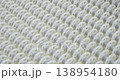 An industrial conveyor is in operation, white plastic rollers are rotating. Static handheld shot of production, sorting, or transportation line, real time speed, artificial lighting. 138954180