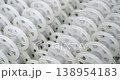 An industrial conveyor is in operation, white plastic rollers are rotating. Static handheld shot of production, sorting, or transportation line, real time speed, artificial lighting. 138954183