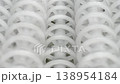 An industrial conveyor is in operation, white plastic rollers are rotating. Static handheld shot of production, sorting, or transportation line, real time speed, artificial lighting. 138954184