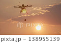 A military drone drops explosives against a sunset and sky. 138955139