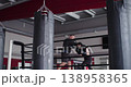 A young Caucasian woman during boxing pads workout with a trainer. She striking the training pads with precision and power, demonstrating discipline, focus, and intense athletic effort. 138958365