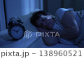 Elderly woman sleeping at night with clock nearby showing time 138960521