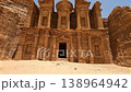 View of the rock-cut facade of the Ad Deir Monastery with an adult man walking across the desert 138964942