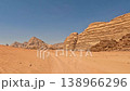 Aerial view of red sand dunes and massive sandstone rock formations with tire tracks leading through 138966296