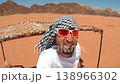 Middle-aged man wearing a keffiyeh and a young woman riding in an open-top vehicle during a desert 138966302