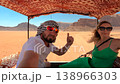 A man in a keffiyeh and a woman in a green dress traveling in the back of a vehicle across the red 138966303