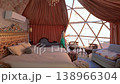 Young woman in a green dress standing inside a luxury geodesic dome tent overlooking the desert 138966304