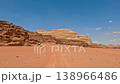 Aerial view of red sandstone rock formations and desert tracks across the valley floor in Wadi Rum 138966486