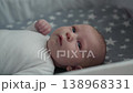 Newborn baby with blue eyes lying in crib star bedding looking curious. Infant child nursery decor family love joy parenthood cozy home adorable moment childhood innocence peaceful calm. 138968331