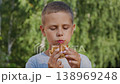 A cute 9-year-old boy eats a burger in the park 138969248