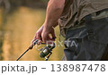 Close up of fisherman hands reeling fishing line with spinning rod. Outdoor leisure activity 138987478