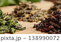 Assorted dried rolled tea leaves arranged on woven bamboo surface with soft foliage background 138990072
