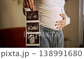 Proud pregnant woman lovingly caressing her growing belly while holding up a sonogram picture of her unborn baby, showing the healthy development and symbolizing the beautiful journey of motherhood 138991680