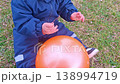 Toddler in blue jumpsuit playing with orange balloon 138994719