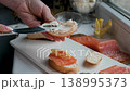 Chef spreads cream cheese on toast, preparing a healthy breakfast or snack. Sliced avocado and smoked salmon await nearby 138995373