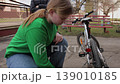 Young woman inflating a bicycle tire with a hand pump 139010185