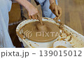 Close up of female hands shaping clay on pottery wheel in ceramic studio, handmade pottery process and traditional craft 139015012