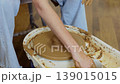 Close up of female hands shaping clay on pottery wheel in ceramic studio, handmade pottery process and traditional craft 139015015