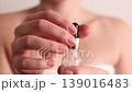 Woman using glass dropper to apply facial serum from cosmetic bottle, skincare routine and beauty treatment concept 139016483