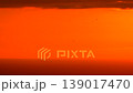 Sunset sky birds: vibrant orange and red sky at dusk with small flock of birds flying high above the warm ocean horizon. 139017470