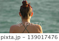 Woman beach ocean, young female in bikini looking at the calm sea in serene summer scene, back view 139017476