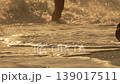 Beach water sunset, person walking into ocean waves at golden hour 139017511