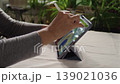 Woman drawing a picture on a tablet screen while sitting in a room at a table 139021036