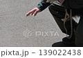 A man checks the road surface temperature by touching it with his hand while walking his dog. 139022438