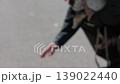 A man checks the road surface temperature by touching it with his hand while walking his dog. (Out of focus) 139022440