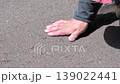 A man checks the road surface temperature by touching it with his hand while walking his dog. 139022441