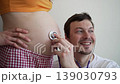 Delighted young father listening to his unborn baby's heartbeat through a stethoscope placed on his pregnant wife's tummy, smiling with overwhelming joy and wonder at the new life 139030793