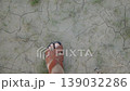 Man feet in sandals walking on dry cracked earth with sparse grass. Drought and climate disasters from first person point of view. 139032286