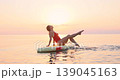 Happy young woman walking on stand up paddle sup board by the sea during summer vacation. Beautiful girl flat water paddling against sea and sky background. Healthy lifestyle concept. Slow motion 139045163