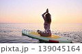 Happy young woman walking on stand up paddle sup board by the sea during summer vacation. Beautiful girl flat water paddling against sea and sky background. Healthy lifestyle concept. Slow motion 139045164