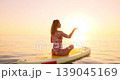 Happy young woman walking on stand up paddle sup board by the sea during summer vacation. Beautiful girl flat water paddling against sea and sky background. Healthy lifestyle concept. Slow motion 139045169