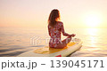 Happy young woman walking on stand up paddle sup board by the sea during summer vacation. Beautiful girl flat water paddling against sea and sky background. Healthy lifestyle concept. Slow motion 139045171