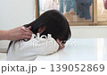 A five-year-old Japanese girl with long hair sleeping with her arm as a pillow on a table, and her grandmother's hand. 139052869