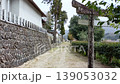 A quiet shrine scene with a large torii gate on the right and a single path along the stone wall. 139053032